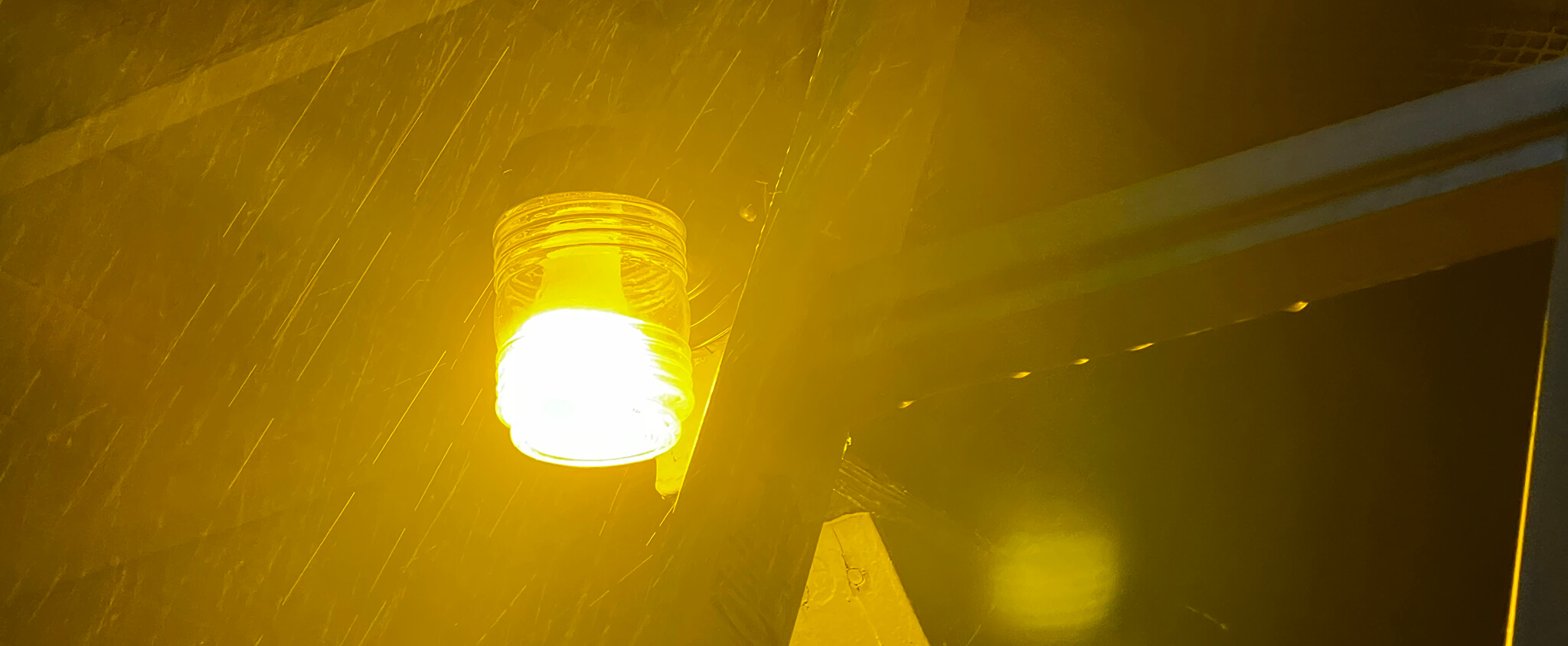 A yellow light bulb in the rain.